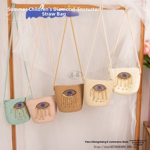 Detail view of handmade straw crossbody bag with embroidered eyes and bead tassels
