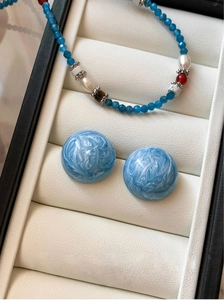 Vue rapprochée de boucles d'oreilles en marbre bleu et collier dans un écrin