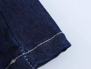 Détail macro du tissu denim bleu foncé avec des coutures contrastantes jaunes