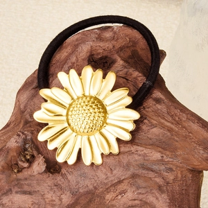 Macro shot of gold daisy hair tie with 304 stainless steel detail on rustic wood