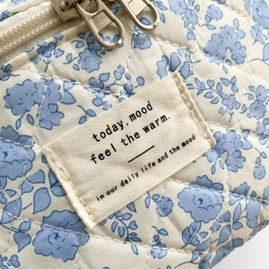 Detailed macro view of quilted floral fabric texture and embroidered mood label on blue bag