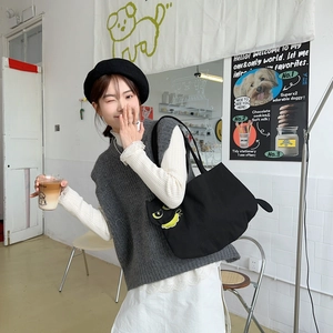 Detail of cute black canvas tote bag with 3D cartoon tail and eyes on shoulder bag