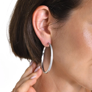 Close-up of large polished silver hoop earring with flat geometric design for women
