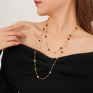 Detailed view of layered gold plated necklace with brown tiger eye beads on a model