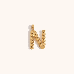 Macro detail of gold-plated letter N pendant featuring a unique twisted metal texture