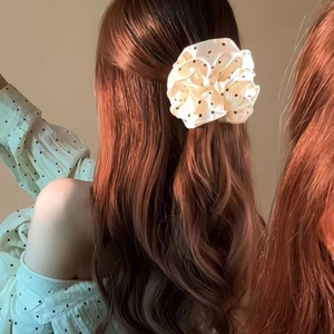 Pince à cheveux fleurie à pois présentée sur la coiffure élégante d'un mannequin