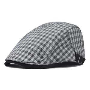 Detailed side view of black and white plaid flat cap with adjustable strap and buckle