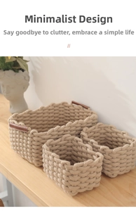 Detail of three woven beige cotton storage baskets with brown leather handles on a wood surface