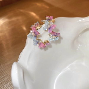 Détail de boucles d'oreilles papillon avec dégradé rose violet et perles blanches