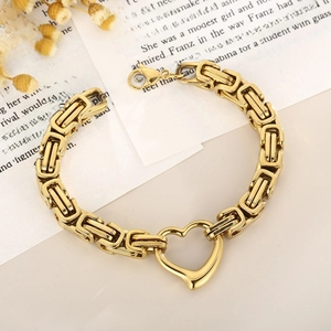 Detail of golden Byzantine chain bracelet with heart-shaped link on vintage book background