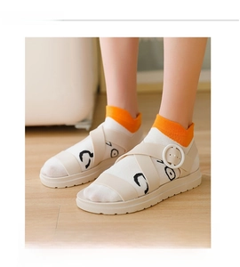 Detail of beige crisscross strap sandals with round buckles and cartoon eye print socks