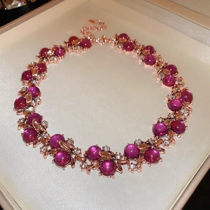 Close-up of rose gold necklace with magenta gemstone and diamonds in a beige jewelry box