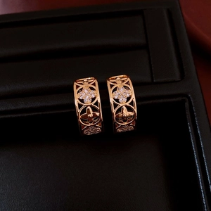 Detailed macro of gold plated hollow clover earrings with rhinestones on black display