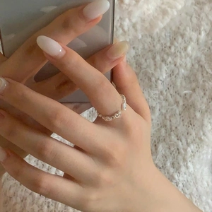 Close-up of S925 sterling silver ring with hollow heart patterns on plush white background