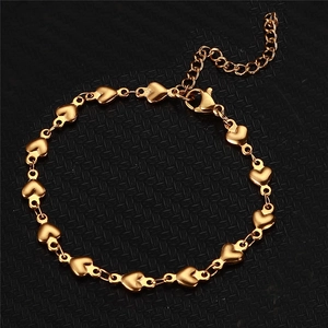Macro d'un bracelet chaîne à cœurs dorés avec fermoir mousqueton et chaînette de réglage