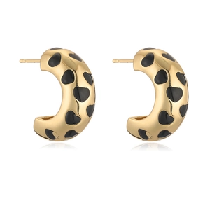Golden C-shaped hoop earrings with black enamel heart patterns on white background