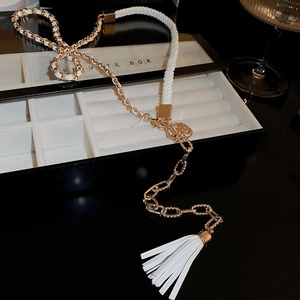 Detail of luxury gold chain body jewelry with white woven leather and tassel accents