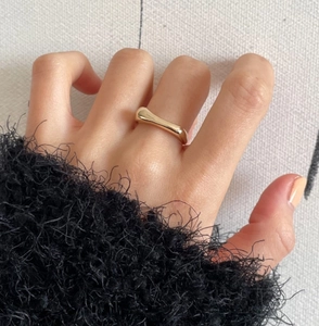Nahaufnahme eines minimalistischen welligen 925er Sterlingsilberrings mit Goldfinish