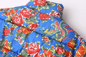 Macro detail of royal blue puffer jacket with phoenix floral embroidery and quilted fabric