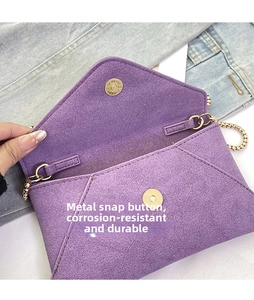 Close-up of golden metal magnetic clasp on purple frosted envelope crossbody bag