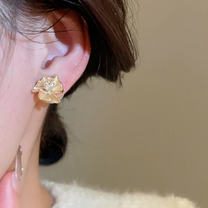 Detail view of 18k gold plated flower stud earrings with zircon stones on model ear