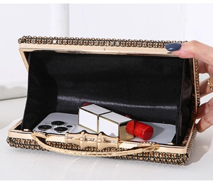 Detail view of gold rhinestone clutch interior showing storage capacity for phone and lipstick