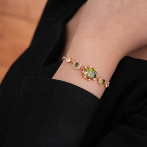 Bracelet ajustable plaqué or avec pierres vert olive et diamants porté au poignet