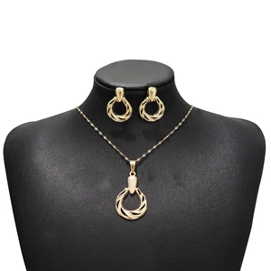 Detail of twisted gold ring necklace and earrings set on a black mannequin