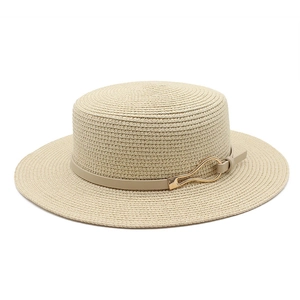 Detail of natural straw sun hat with leather band and gold wavy metal buckle