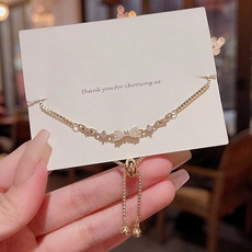 Detail of adjustable gold bow bracelet featuring zircon stones and a sliding bead clasp