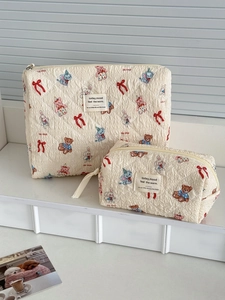 Close-up of quilted cream makeup bags with cartoon animal prints and zipper closure