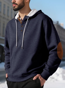 Détail d'un sweat à capuche bleu marine avec empiècements marron contrastés aux coudes