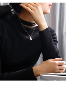 Close-up of gold rectangle letter pendant necklace worn by a model on neck