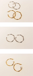 Detailed comparison of gold and silver twisted wavy hoop earrings with metal texture
