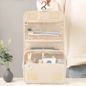 Hanging travel toiletry bag in beige with multiple mesh compartments and hook