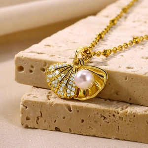 Detail of shell-shaped gold pendant with a pink-white pearl on a beige stone