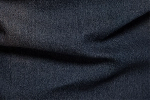 Close-up of high-quality dark denim fabric texture showing tight weave and fiber detail