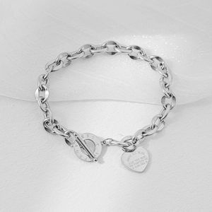 Silver stainless steel toggle bracelet with engraved heart pendant on white organza cloth