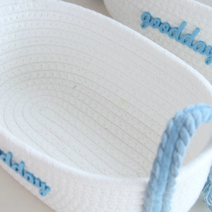Detailed view of white cotton rope storage basket with blue goodday embroidery and handles