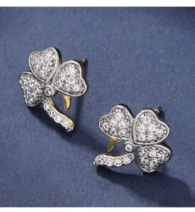 Macro detail of silver clover earrings with micro-set zircons and 14K gold accents