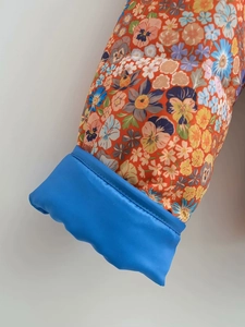 Detail of floral printed jacket sleeve with bright blue ribbed cuffs and quilted texture