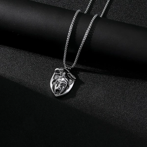 Vue détaillée du pendentif bouclier en acier argenté avec relief de visage et chaîne