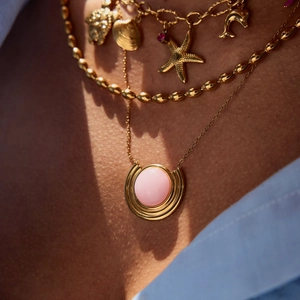 Détails de colliers dorés superposés avec pendentif opale rose et breloques marines