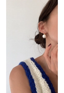 Detailed view of a 925 silver large white pearl earring with gold clasp on a model