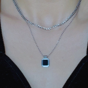 Detail of silver double layered necklace featuring a black square pendant on model
