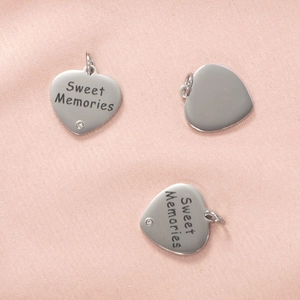 Pendentif cœur en acier inoxydable gravé Sweet Memories sur fond texturé rose