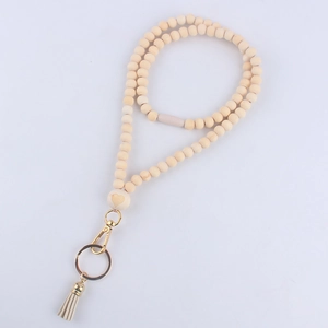 Detail of wooden bead lanyard with heart carving, gold lobster clasp and beige leather tassel