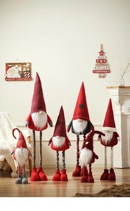 Christmas gnomes in red, grey, and white plush fabric displayed on a cozy wooden floor