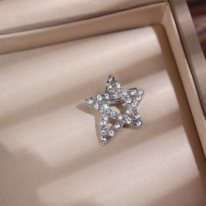 Macro di una spilla a stella d'argento con strass scintillanti su raso beige