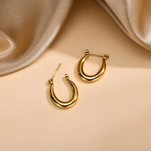 Polished 18K gold stainless steel geometric U-shaped hoop earrings on silk fabric